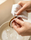 A person carefully cleaning beaded gemstone bracelets