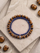 A Tigers Eye 6mm and Deep Blue 4mm bracelet on a textured stone background.