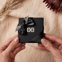 A person holding a Baxter&Baxter gift box with ribbon