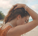 A woman wearing pearl bracelets and a pearl necklace on a beach