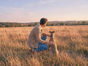A man kneeling by his dog in the Suffolk countryside
