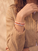 A close-up of a person wearing a stack of 4mm beaded bracelets