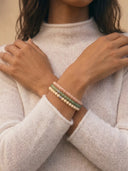 A close-up of a person wearing a stack of 4mm beaded bracelets.