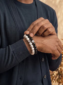 A close-up of a person wearing a stack of 8mm beaded bracelets.