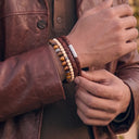 A close-up of a person wearing a Chocolate woven leather bracelet with Ivory and Tiger Eye gemstone bracelets