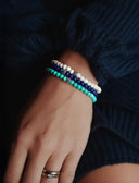Close-up of a wrist wearing a stack of blue and turquoise bracelets
