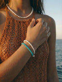 A woman wearing pearl jewellery by the ocean