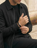 A man wearing a black leather bracelet and black outfit