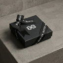 Black gift box with black ribbon on a gray surface