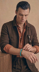 A man wearing turquoise and tigers eye beaded bracelets