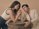 A man and woman arm wrestling while wearing colourful gemstone bracelets