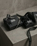 A luxurious black branded gift box with black ribbon and a black pouch