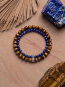 A tigers eye bracelet and lapis lazuli bracelet on a textured stone background 