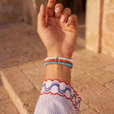 A close-up of a person wearing Snow, Burnt Orange and Turquoise beaded bracelets