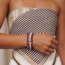 A close-up of a woman wearing Amethyst, Snow and Tiger Eye bracelets