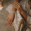 Close-up of a person's wrist with a stack of  ivory, turquoise and white gemstone bracelets