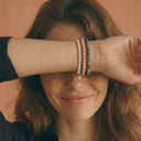 A woman wearing a stack of beaded gemstone bracelets