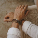 Close-up of a person's wrist wearing a brown woven leather bracelet