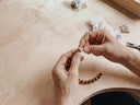 A craftsman assembling a tigers eye bracelet in our workshop